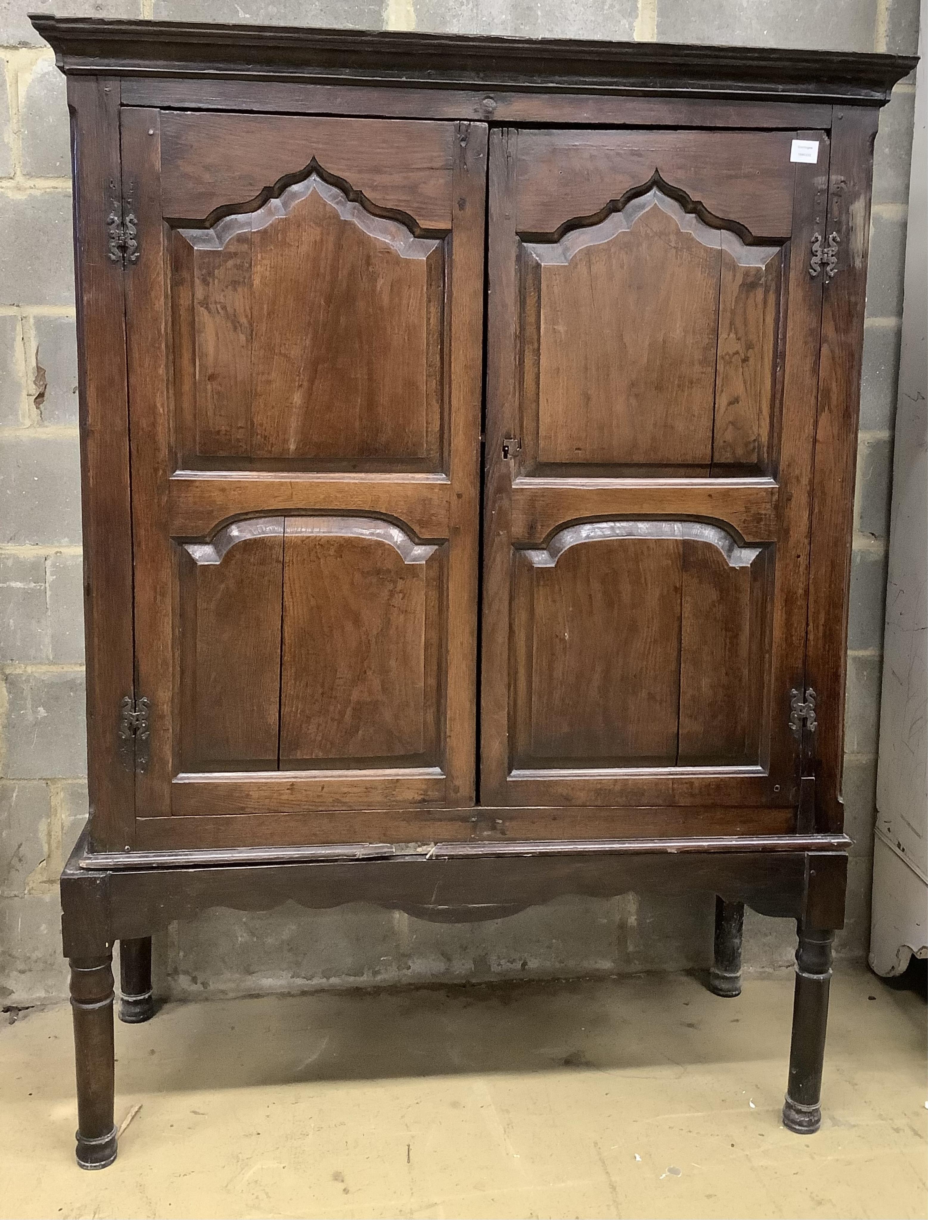 A mid 18th century carved oak cupboard, on associated stand, a.f., width 130cm, depth 55cm, height 178cm. Condition - poor